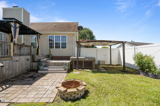 back of house featuring a fire pit, cooling unit, a yard, a wooden deck, and a patio area