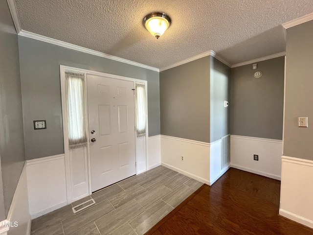 entryway with ornamental molding and a textured ceiling