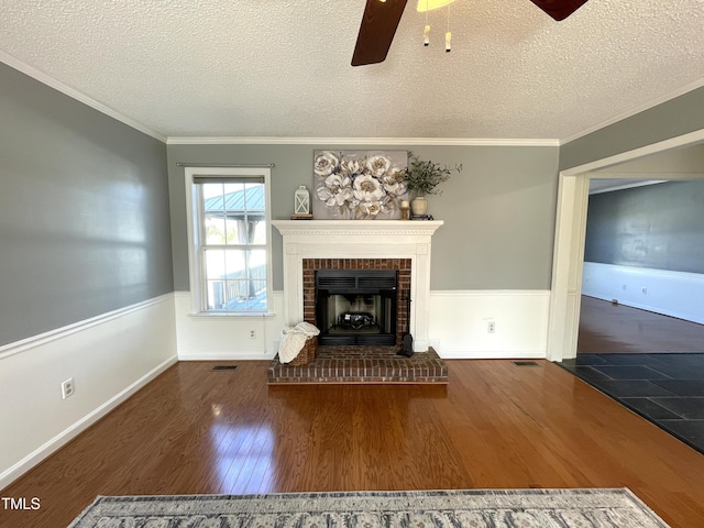 unfurnished living room with a brick fireplace, dark wood-type flooring, ornamental molding, and a textured ceiling