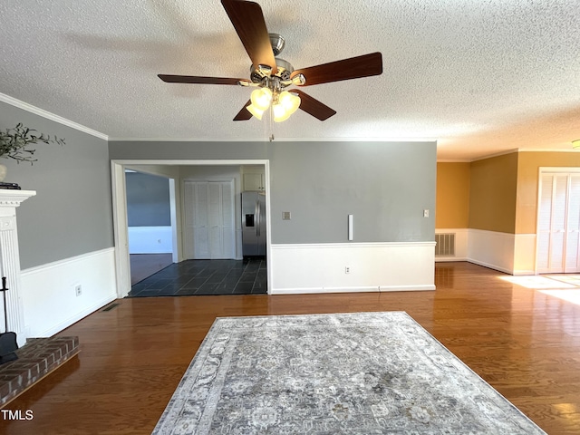 unfurnished room featuring ornamental molding, dark hardwood / wood-style floors, a brick fireplace, and a textured ceiling