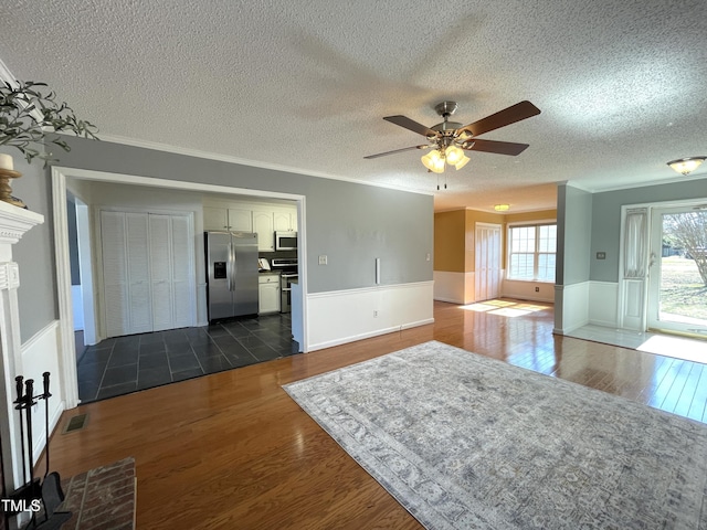 interior space featuring ornamental molding, dark wood-type flooring, a textured ceiling, and ceiling fan