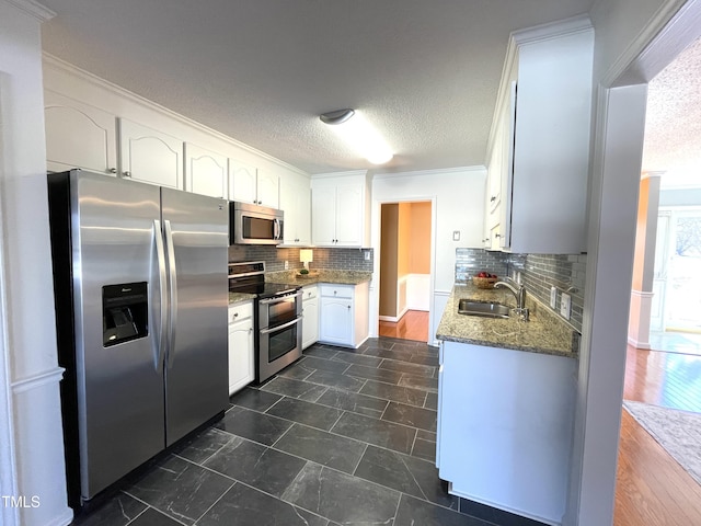 kitchen with white cabinetry, stainless steel appliances, sink, and a textured ceiling