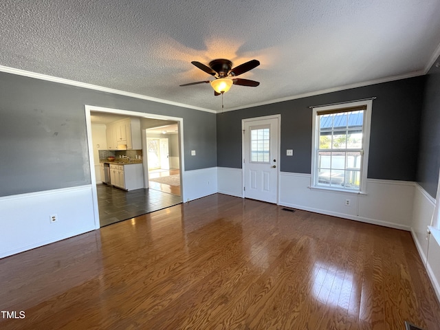 empty room with crown molding, ceiling fan, dark hardwood / wood-style flooring, and a textured ceiling