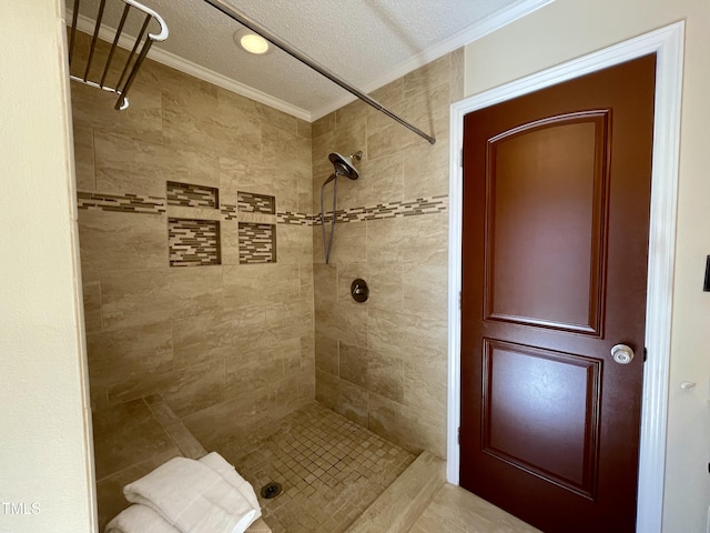 bathroom featuring a textured ceiling, ornamental molding, and tiled shower