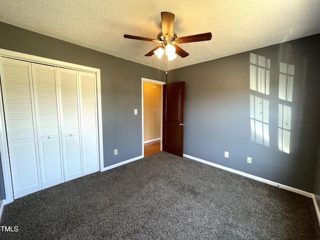 unfurnished bedroom featuring ceiling fan, a closet, dark carpet, and a textured ceiling