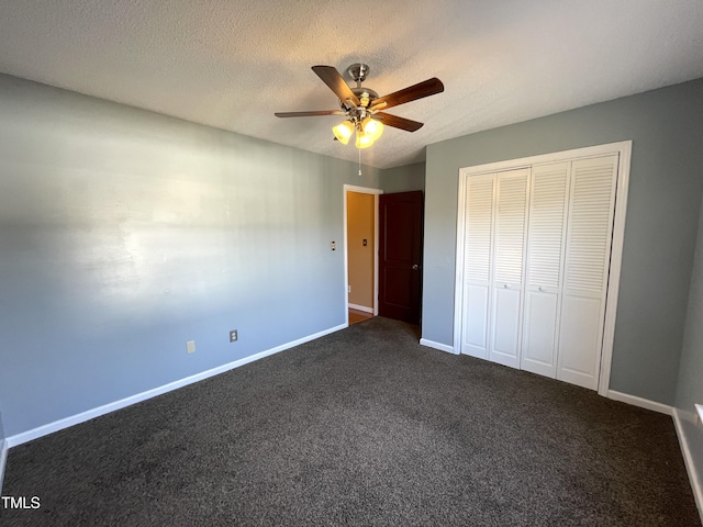 unfurnished bedroom featuring ceiling fan, a closet, a textured ceiling, and dark colored carpet