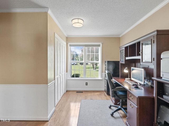 home office featuring visible vents, baseboards, ornamental molding, light wood-style flooring, and a textured ceiling