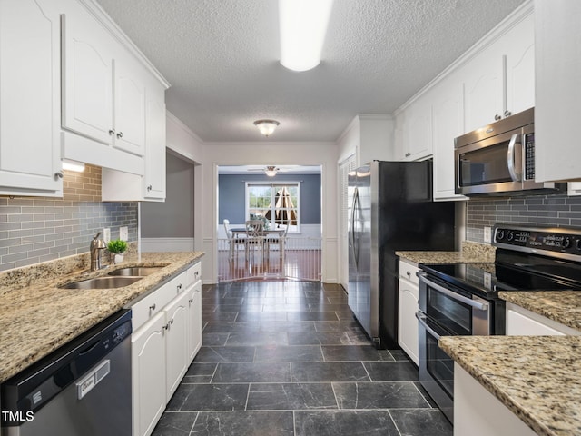 kitchen with white cabinetry, a wainscoted wall, appliances with stainless steel finishes, and a sink