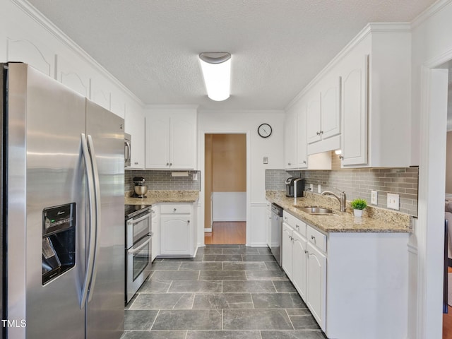 kitchen featuring appliances with stainless steel finishes, white cabinetry, and a sink