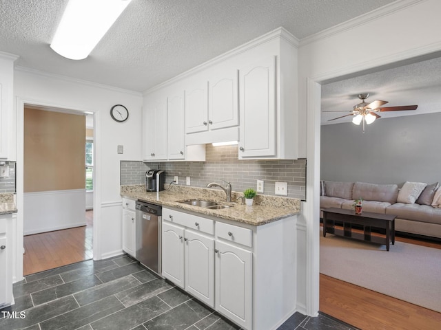 kitchen with stainless steel dishwasher, white cabinets, light stone countertops, and a sink