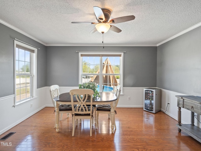 dining area featuring wood finished floors, beverage cooler, visible vents, and a wealth of natural light