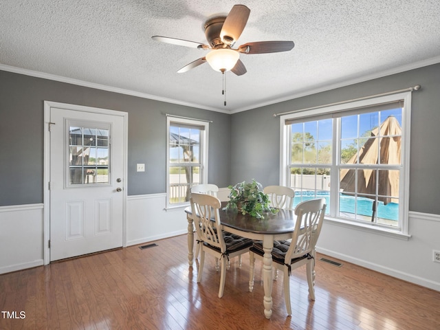 dining area featuring a wealth of natural light, visible vents, wood-type flooring, and ornamental molding