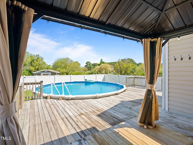 view of pool featuring a gazebo, a fenced in pool, a fenced backyard, and a deck