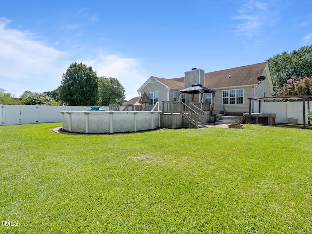 view of yard with an outdoor pool, a wooden deck, a fenced backyard, and a gate