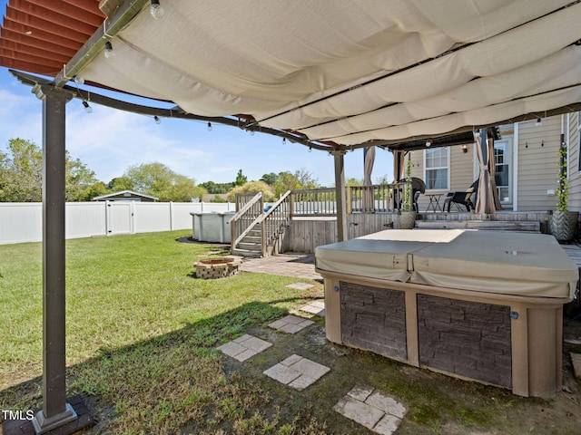 view of yard featuring a fire pit, a wooden deck, a fenced backyard, and a hot tub