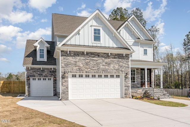 view of front of home with fence, driveway, a shingled roof, stone siding, and board and batten siding