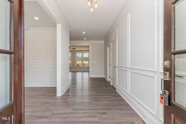 hallway featuring wood finished floors, baseboards, recessed lighting, ornamental molding, and a decorative wall