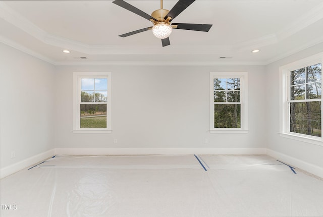 carpeted empty room with a raised ceiling, ceiling fan, and ornamental molding