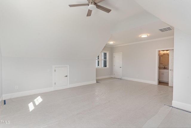 interior space featuring visible vents, baseboards, lofted ceiling, ornamental molding, and a ceiling fan