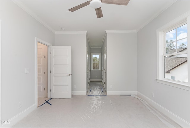 unfurnished bedroom with ceiling fan, baseboards, multiple windows, and ornamental molding