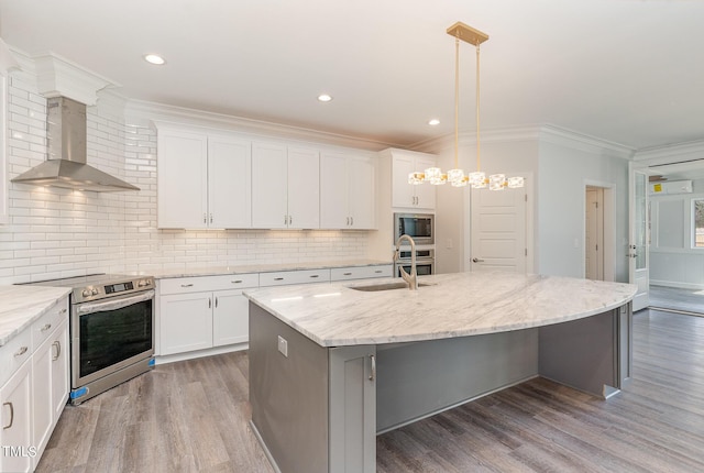 kitchen featuring crown molding, wall chimney range hood, an island with sink, stainless steel appliances, and a sink