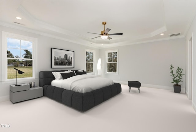 carpeted bedroom featuring visible vents, multiple windows, a raised ceiling, and ornamental molding