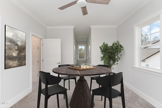 dining room with ceiling fan, ornamental molding, and light carpet