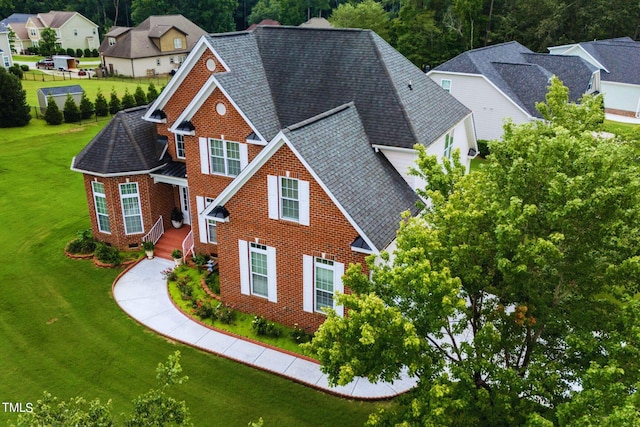 view of front of property with crawl space, roof with shingles, a front yard, and brick siding