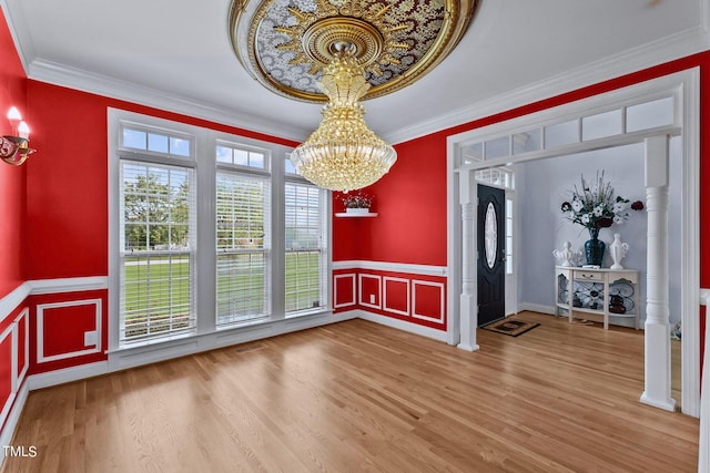 unfurnished dining area with a notable chandelier, crown molding, and wood finished floors