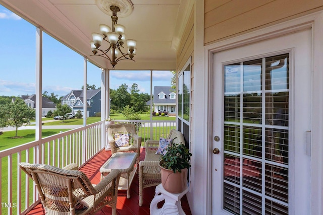 sunroom with a residential view and a notable chandelier