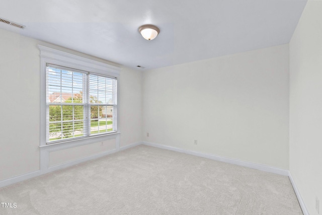 empty room with light colored carpet, visible vents, and baseboards