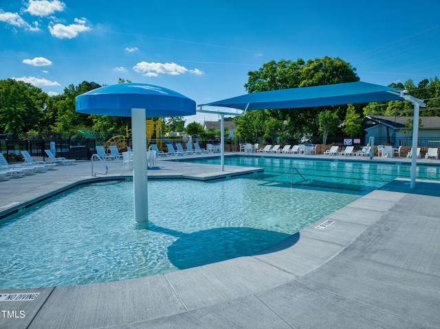 community pool with a patio area and fence