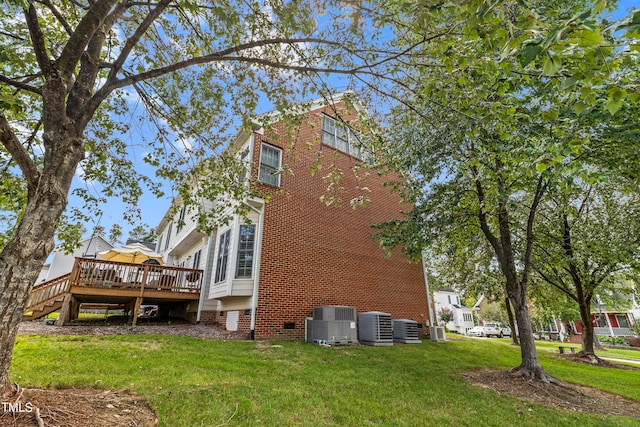 rear view of house featuring central air condition unit, a wooden deck, and a yard