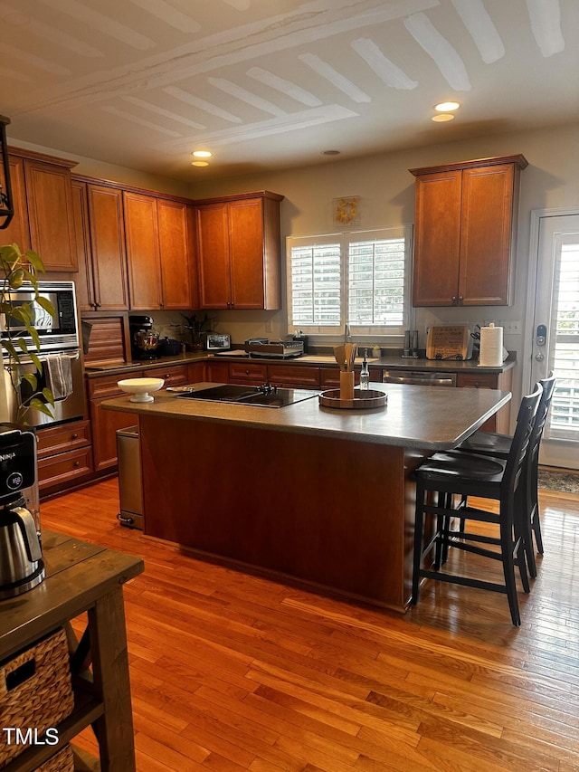 kitchen with a healthy amount of sunlight, appliances with stainless steel finishes, hardwood / wood-style flooring, and a kitchen island