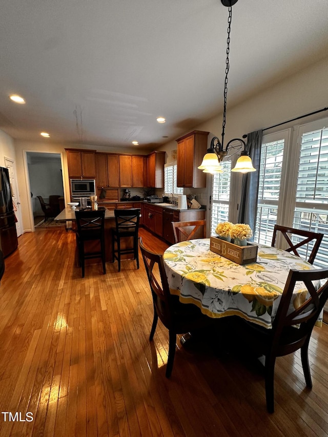 dining area featuring a healthy amount of sunlight, hardwood / wood-style floors, an inviting chandelier, and sink