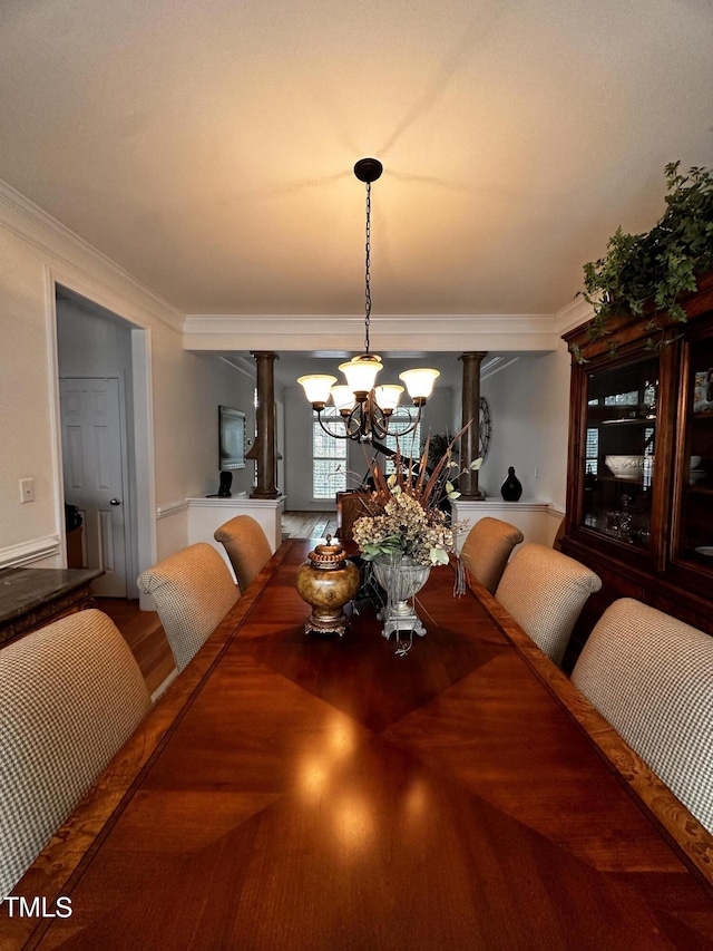 dining room featuring crown molding, hardwood / wood-style flooring, an inviting chandelier, and decorative columns