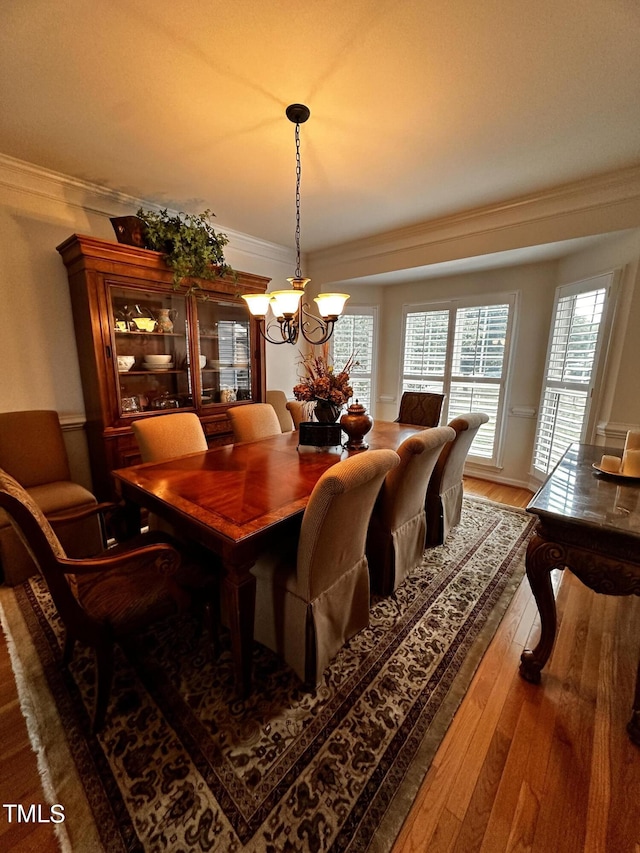 dining space with ornamental molding, hardwood / wood-style flooring, and an inviting chandelier