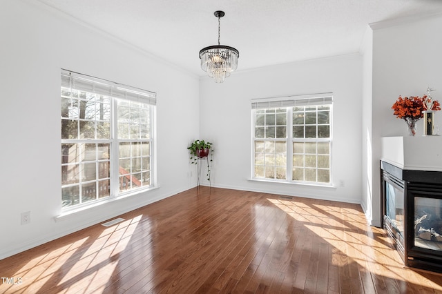 unfurnished living room with hardwood / wood-style flooring, plenty of natural light, visible vents, and crown molding