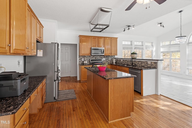 kitchen with wood-type flooring, a center island, a peninsula, stainless steel appliances, and a sink