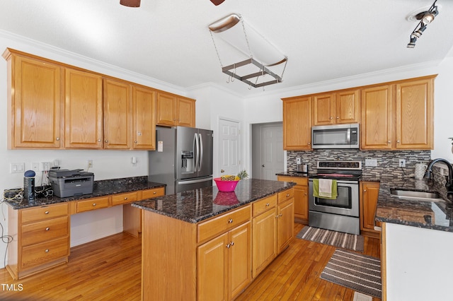 kitchen with a kitchen island, appliances with stainless steel finishes, ornamental molding, light wood-style floors, and a sink