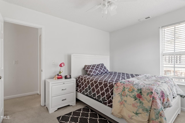 bedroom with visible vents, a ceiling fan, and light colored carpet