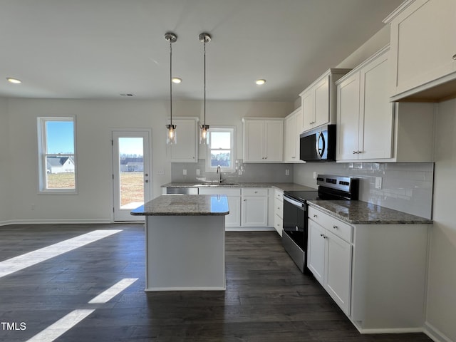 kitchen featuring white cabinetry, appliances with stainless steel finishes, a sink, and a center island