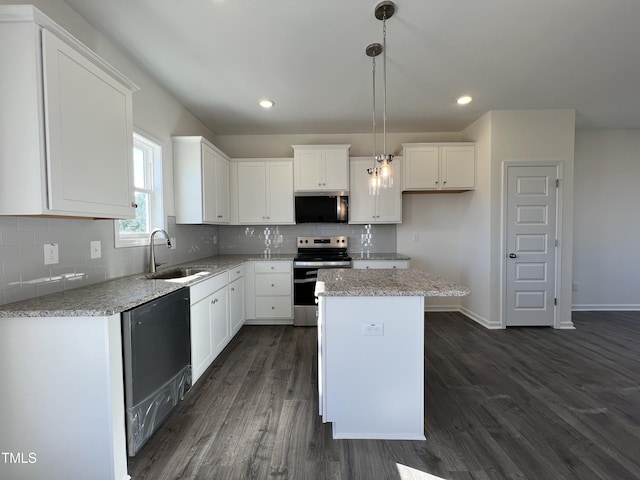 kitchen with a center island, stainless steel appliances, white cabinetry, a sink, and light stone countertops