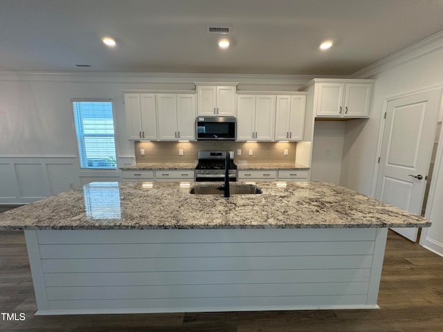 kitchen featuring appliances with stainless steel finishes, a center island with sink, and dark wood-type flooring