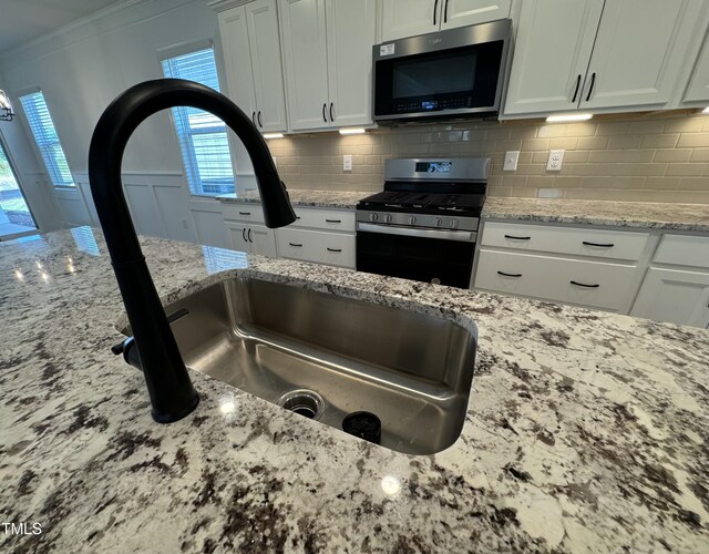 kitchen featuring a wealth of natural light, decorative backsplash, light stone counters, and stainless steel appliances