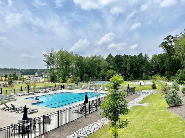 community pool with a patio, a yard, and fence