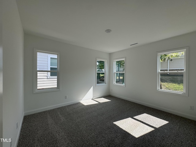 carpeted spare room featuring baseboards, plenty of natural light, and visible vents