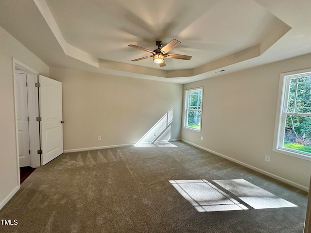 carpeted spare room featuring a raised ceiling and ceiling fan