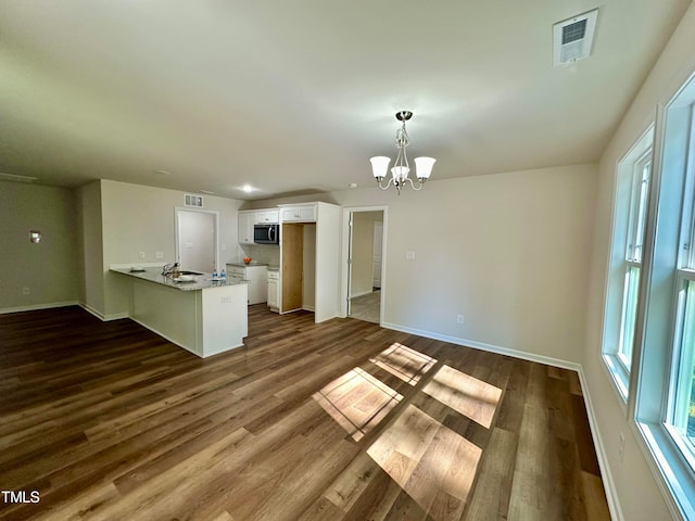 kitchen featuring plenty of natural light, dark hardwood / wood-style floors, white cabinets, decorative light fixtures, and kitchen peninsula