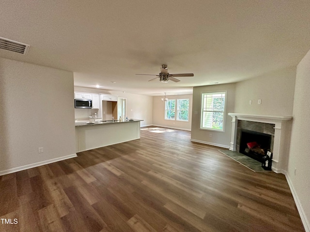 unfurnished living room with dark wood-type flooring, ceiling fan, and a fireplace